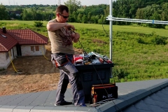 W słoneczny letni dzień praca instalatora RTV na dachu